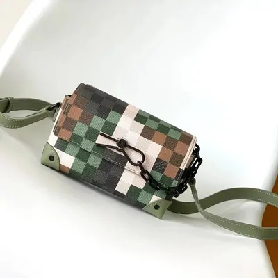 A camouflage-check shoulder bag with a green webbing strap on a white surface
