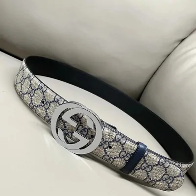 A patterned canvas belt with a round interlocking buckle, coiled on a cream sofa