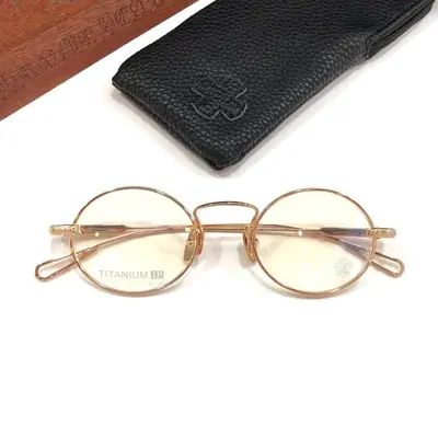 Round gold-rimmed glasses resting on a folded black leather case
