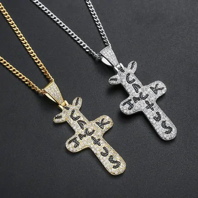 Two stone-set cross pendants hanging from chain necklaces on a dark surface