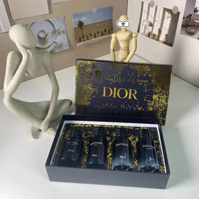 An open dark blue gift box containing three fragrance bottles, photographed on a pale surface.